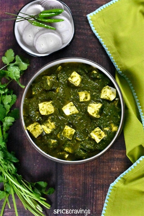 Palak paneer served with sliced onions.