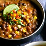 Black bean chili with corn and peppers, served with a wedge of lime