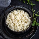 instant pot cumin rice in black bowl served with fresh herbs
