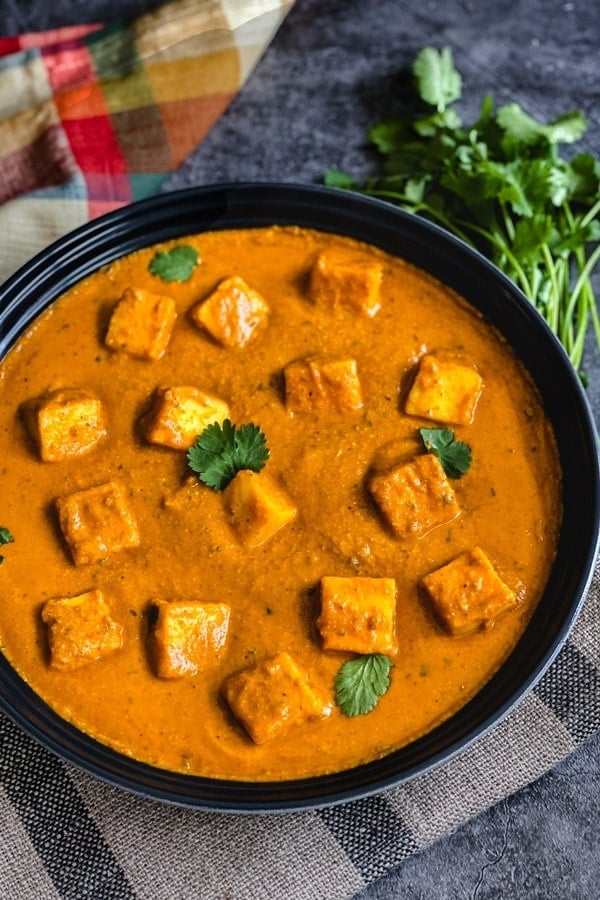 Paneer cubes in a tomato sauce garnished with cilantro leaves