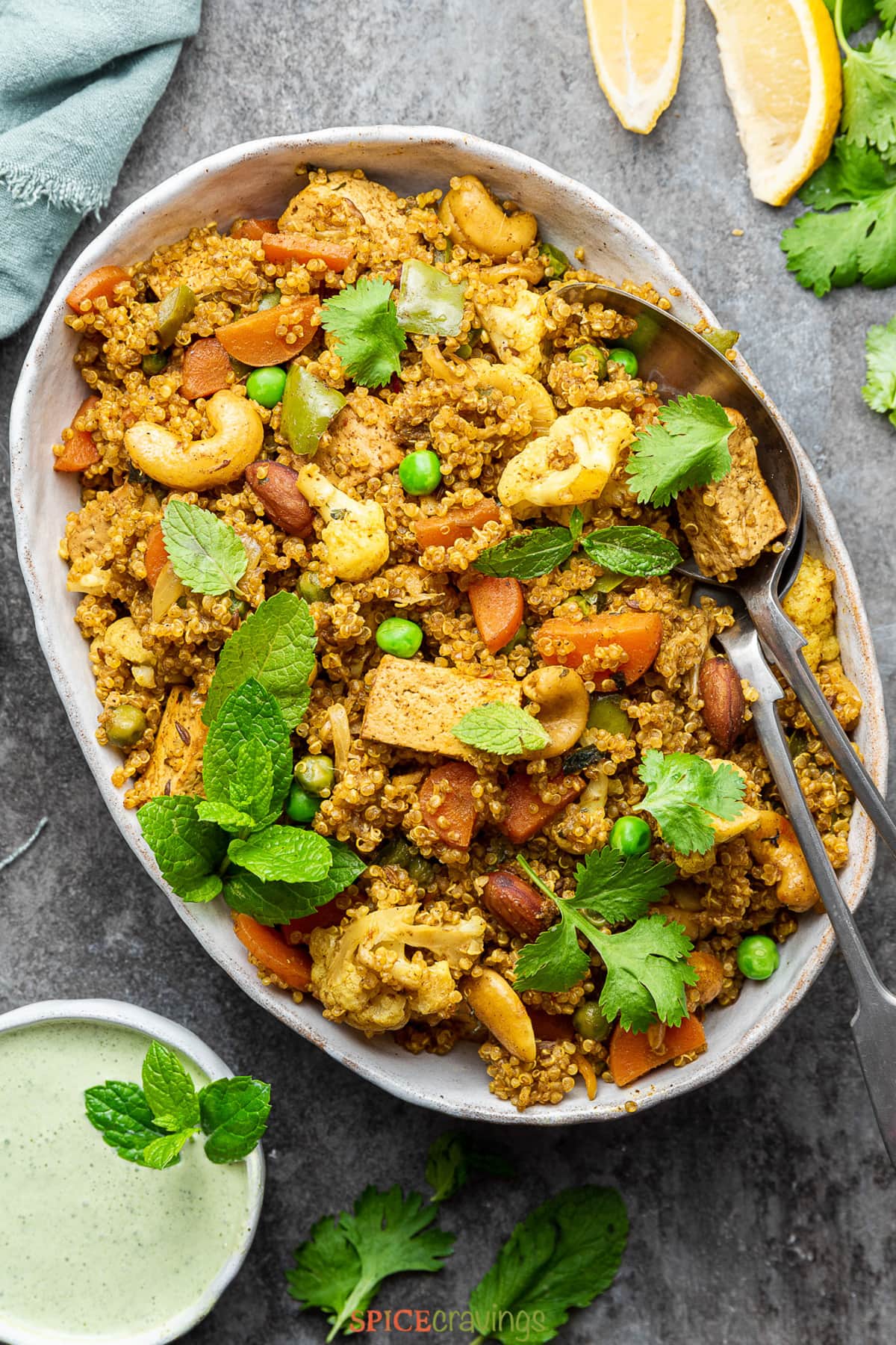 Quinoa and vegetable pilaf in white oval dish, garnished with herbs