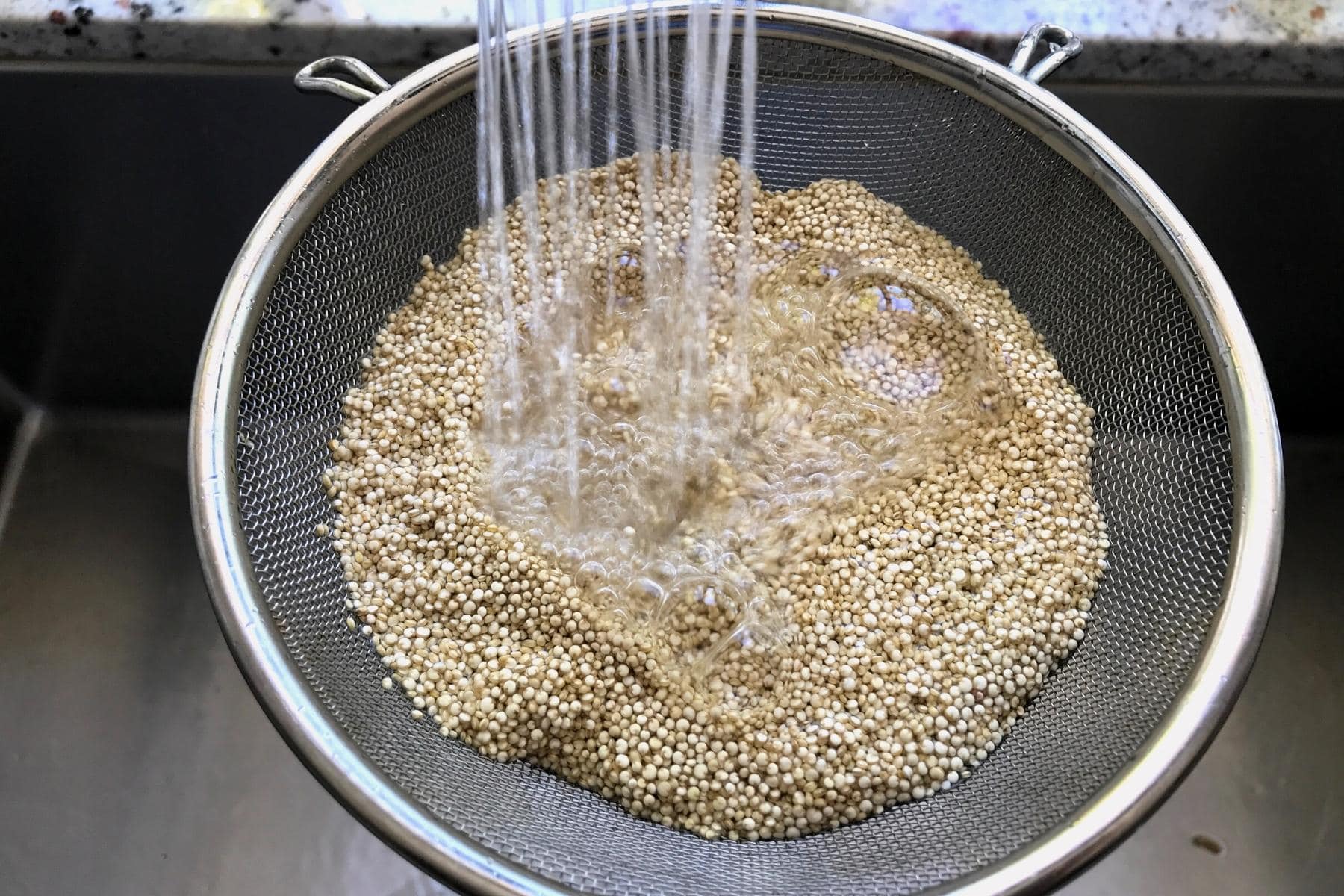 Rinsing quinoa in a fine mesh sieve