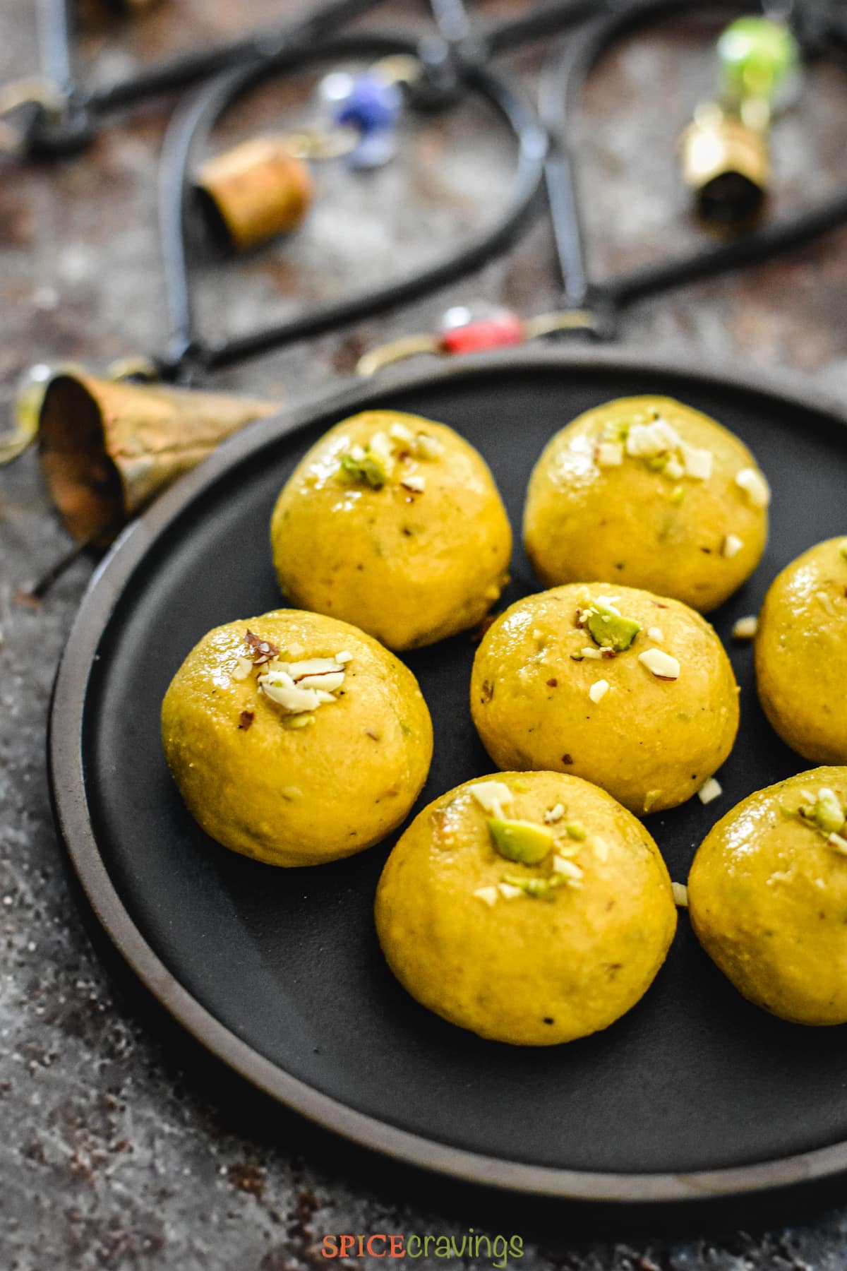A plate of Besan Ladoo next to decorative bells