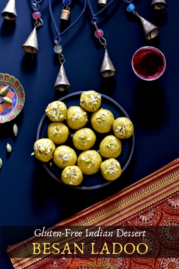 A plate of besan ladoo, chickpea flour fudge, placed next to bells on a decorative placemat