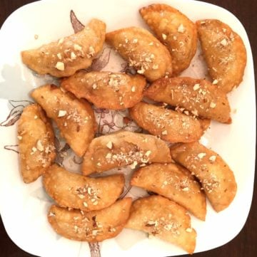 Deep Fried Gujiya, by Spice Cravings. Deep Fried Gujiya, or Milk Fudge Turnovers, are a popular dessert made in the northern part of India around the festivals of Holi and Diwali. It is a deep-fried sweet dumpling that is made by stuffing pastry dough with sweetened milk fudge (khoya), chopped nuts and coconut flakes and is glazed with a thick sugar syrup. #cooking #food #recipe #recipes #foodphotography #foodblogger #yummy #delicious #foodie