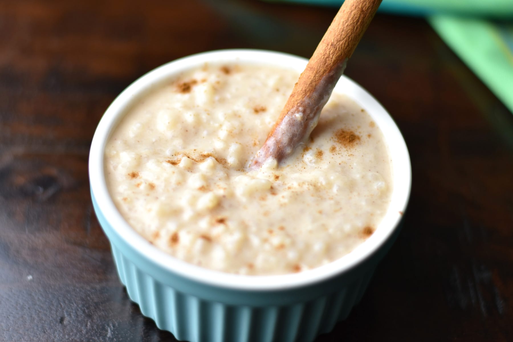 arroz con leche in small blue bowl with wooden spoon