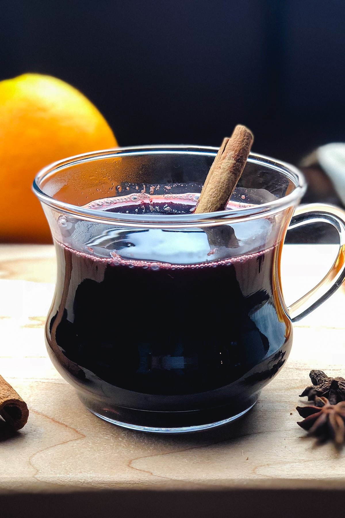 Mulled wine served in a glass cup, garnished with a cinnamon stick.