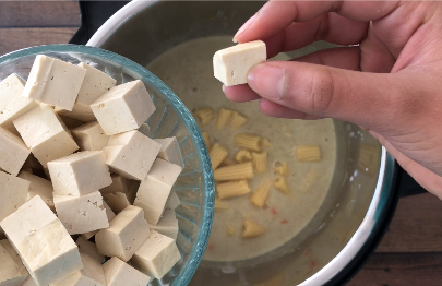 Adding cubed extra firm tofu to the curry