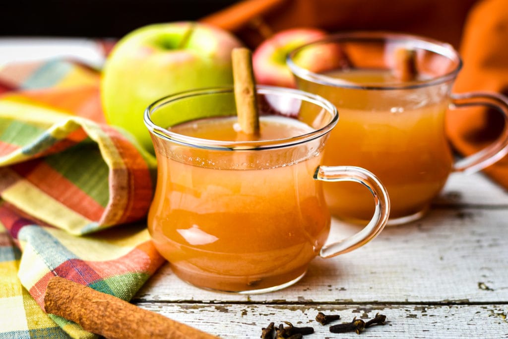 two mugs of hot Apple Cider with cinnamon sticks