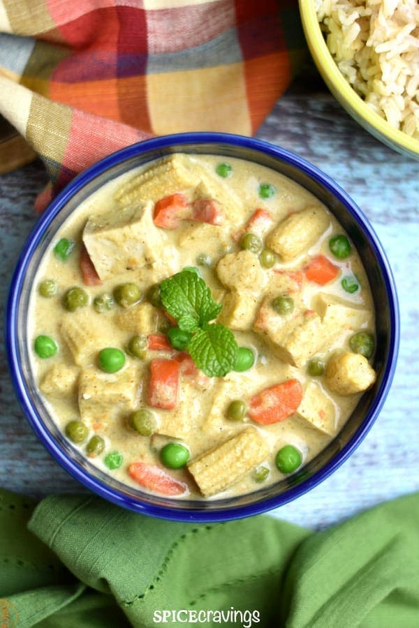 Thai green curry with carrots, peas, baby corn and Tofu served in a blue bowl