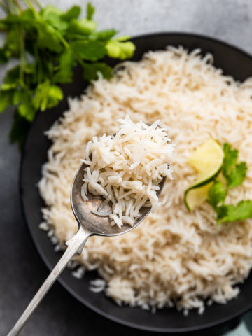A dome of cooked coconut rice garnished with dried coconut and cilantro