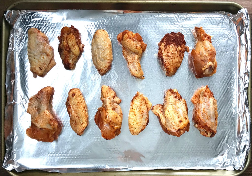 Spiced chicken wings placed on a lined baking sheet