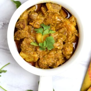 Indian spiced goat curry garnished with a cilantro sprig
