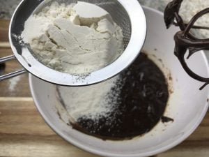 Sifting flour into a bowl with melted chocolate