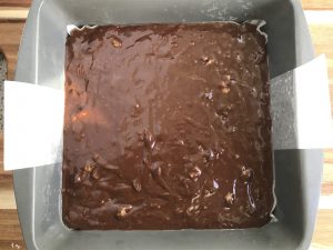 Brownie batter in a parchment lined cake pan