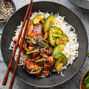 Korean chicken served over rice with pickled cucumber
