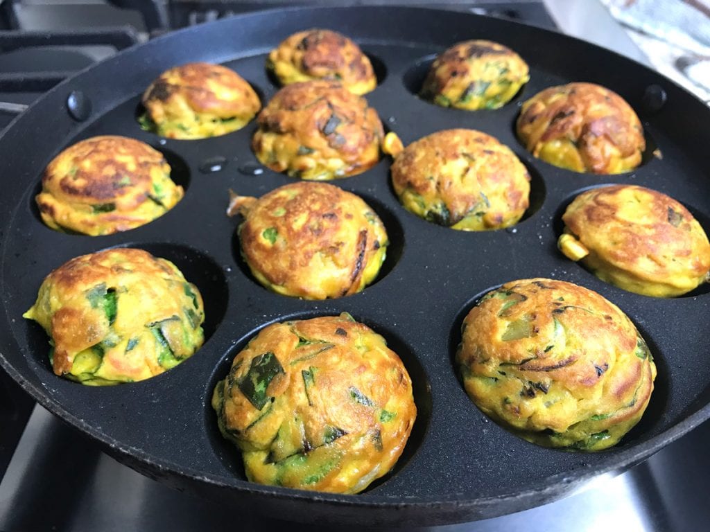 Onion spinach pakoras or fritters being made in a pan, without frying