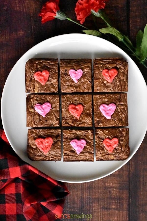 A white plate with Chocolate Brownies decorated with heart shaped icing for Valentine's Day