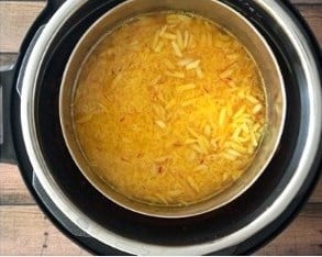 Steel bowl with rice, saffron and almonds placed inside the instant pot