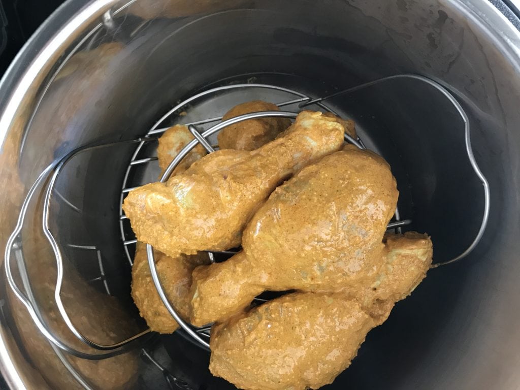 marinated chicken legs placed on a trivet inside an electric pressure cooker