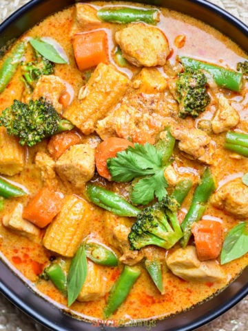 Bowl of thai curry with vegetables and chicken garnished with cilantro
