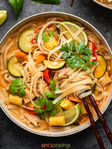 Curry soup in bowl with vegetables, noodles and chicken