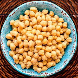 cooked chickpeas in a blue bowl and white background