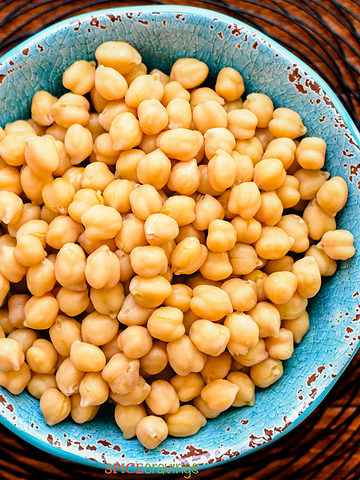 cooked chickpeas in a blue bowl and white background