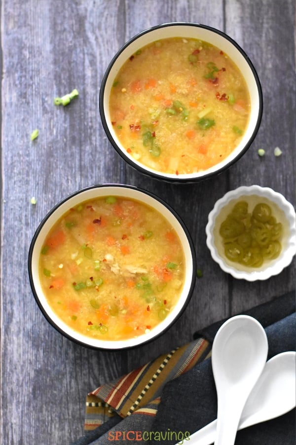 Two bowls of chicken corn soup with a chili vinegar garnish