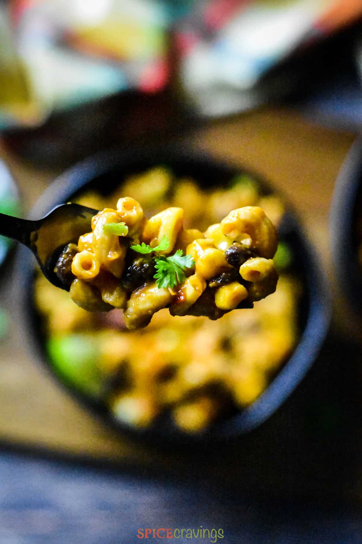 Fork loaded with cheesy pasta with beans, corn and cilantro