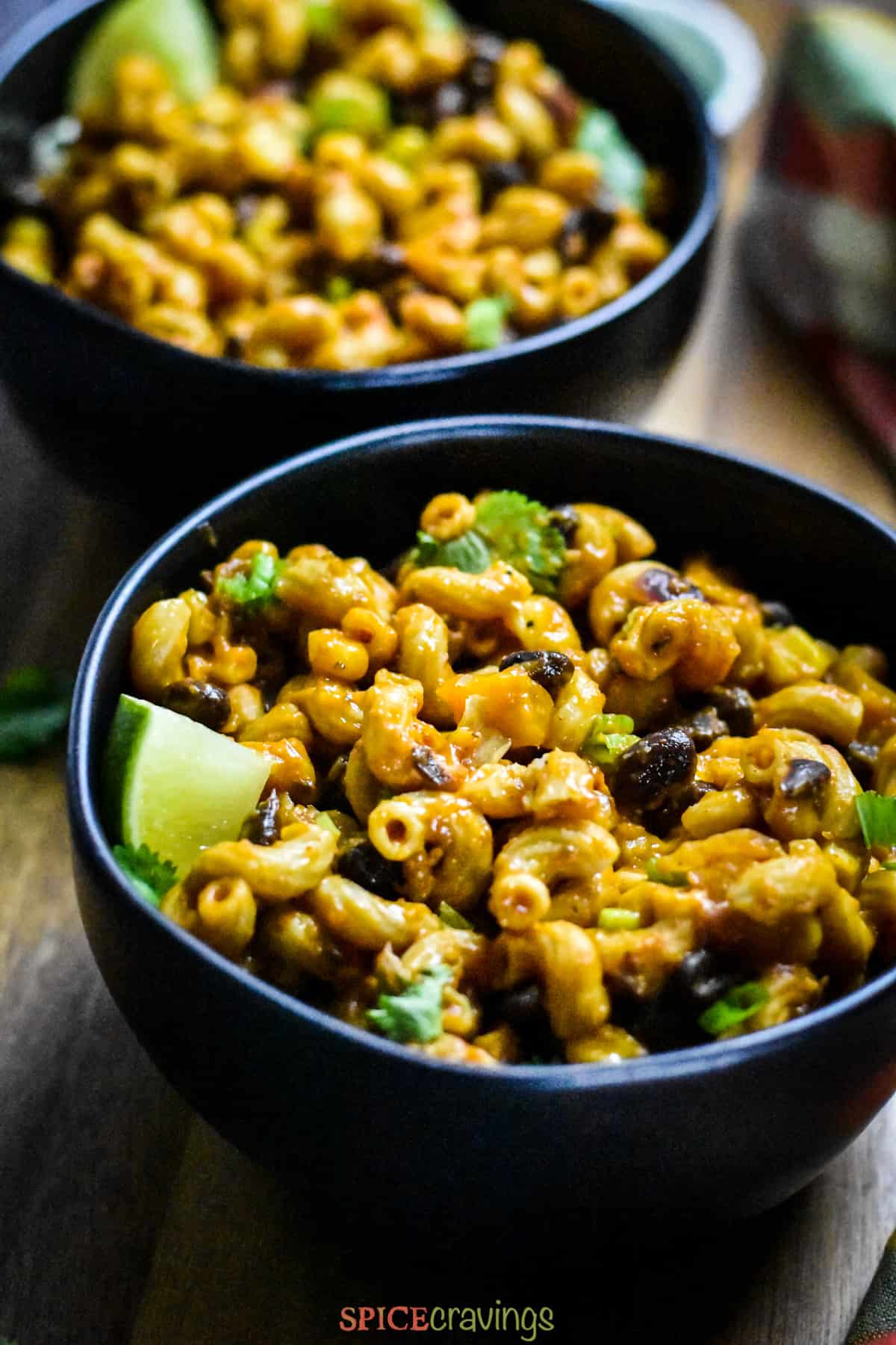 two bowls with cheesy macaroni with black beans and cilantro