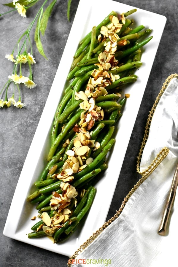 String beans steamed and sautéed with almonds and served on a gray backdrop