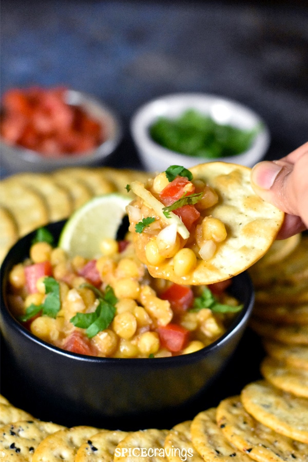 Using a cracker to scoop Indian Spiced white peas dip called Matar Chaat