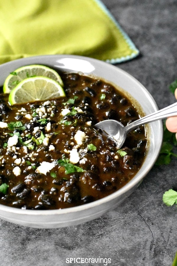 Black beans in a grey bowl, garnished with cilantro and cotija cheese