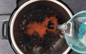 Adding water to the pressure cooker to cook black beans