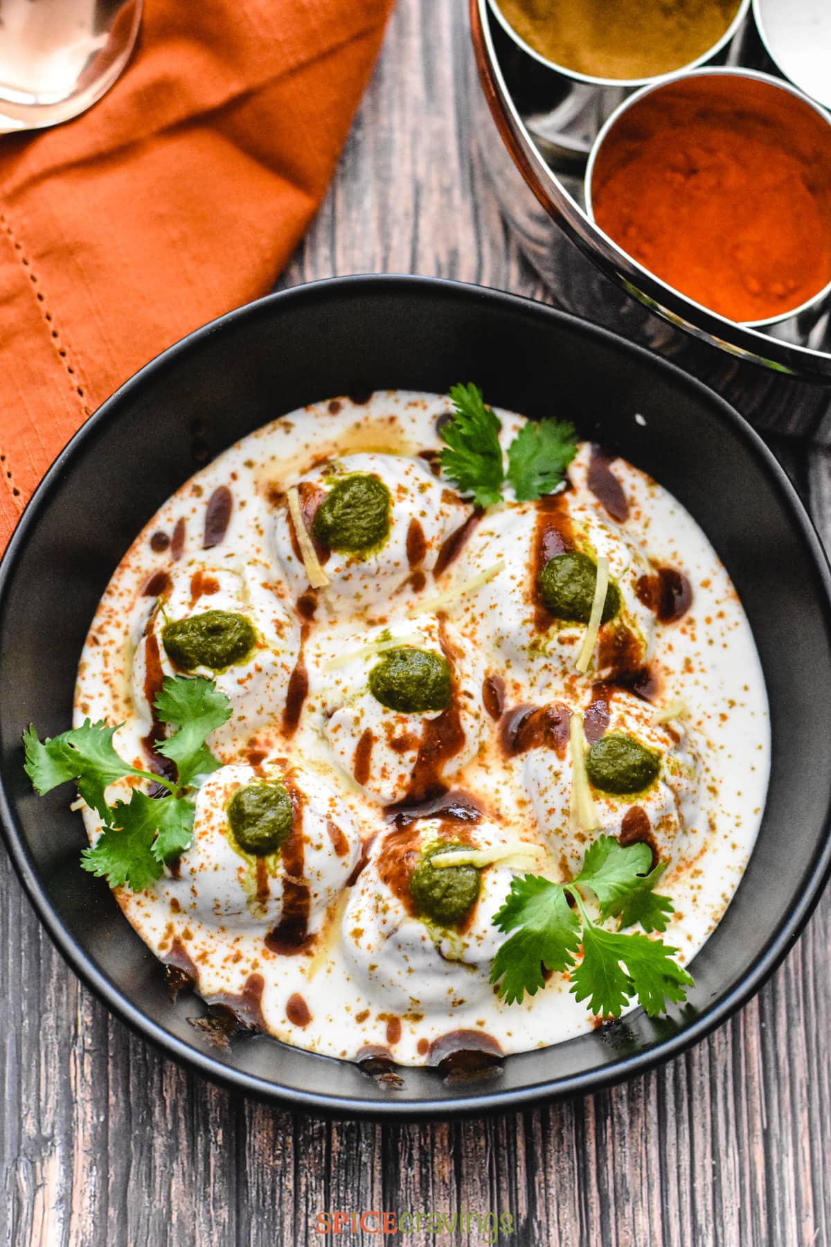 No fry Dahi Bhalle served in a bowl garnished with cilantro and chutney