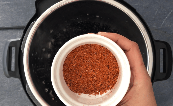 Adding spice blend to the pot to make black beans