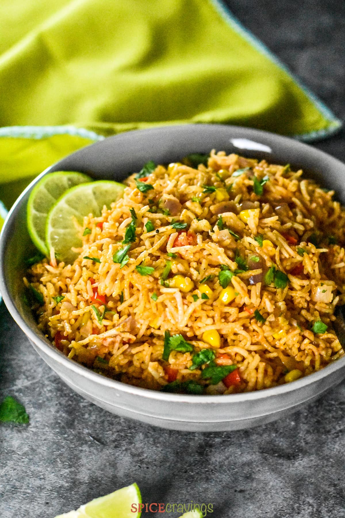 Colorful mexican rice served in a grey bowl with a lime green napkin