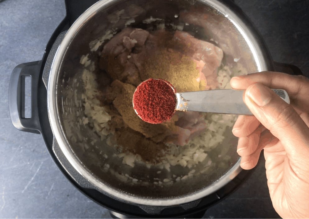 Adding red chili powder to the pot