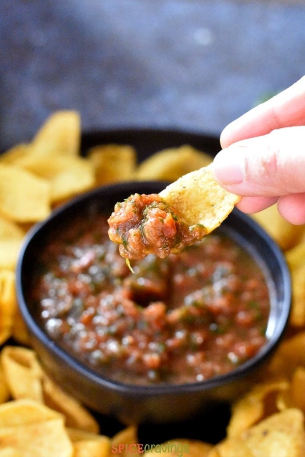 Dipping a corn chip in a bowl of homemade salsa