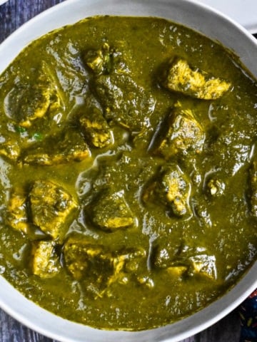 Bowl of spinach curry with chicken cubes