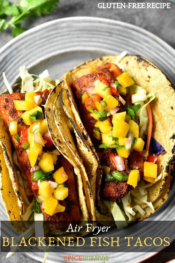 Two grilled fish tacos on a plate garnished with mango salsa