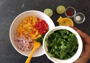 Adding chopped onion and red pepper to the chopped mango