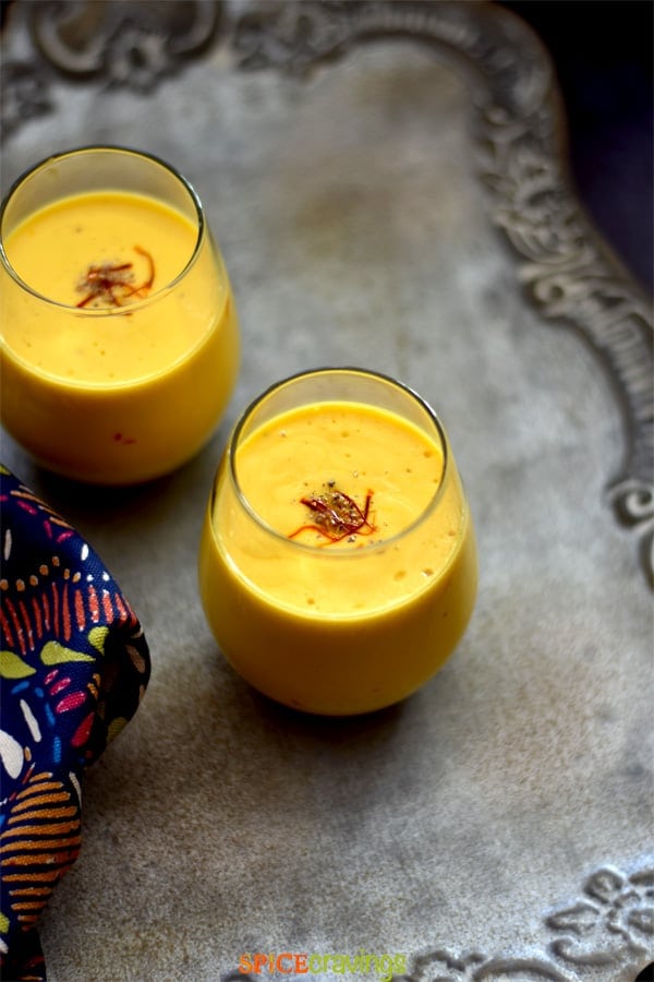 Two glasses of mango lassi garnished with saffron