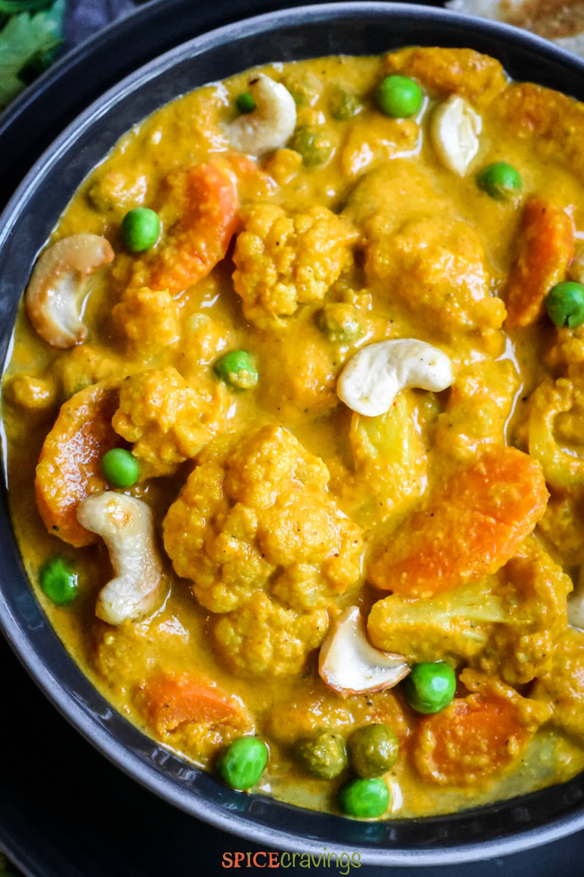 cauliflower, carrots, peas and cashew in korma curry in bowl