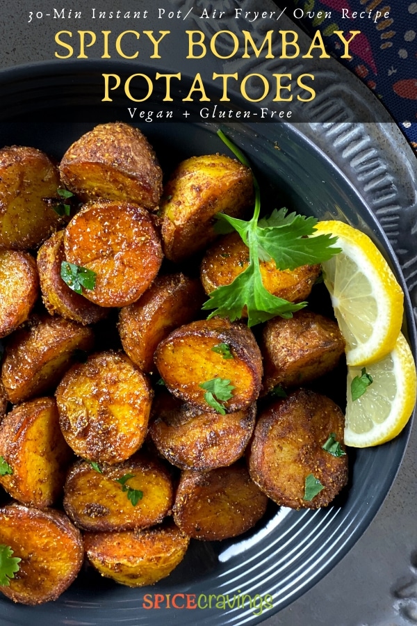 A bowl of spicy bombay potatoes with a garnish of lemon and cilantro