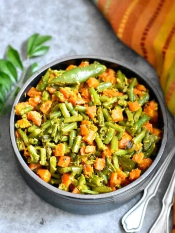 Green beans and carrots with coconut served with curry leaves in the backdrop