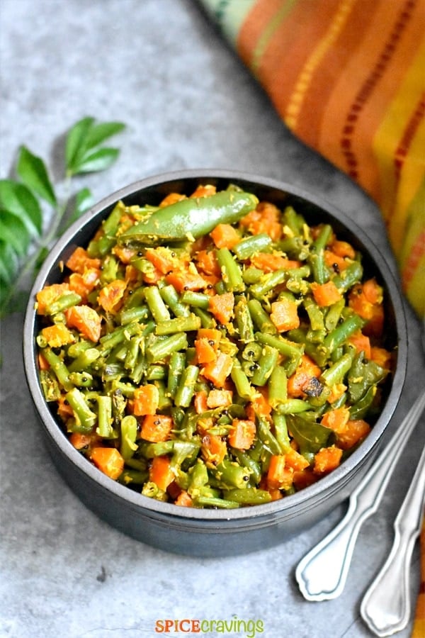 Green beans and carrots with coconut served with curry leaves in the backdrop