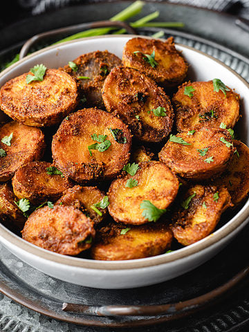 Spicy roasted bombay potatoes served in a black bowl