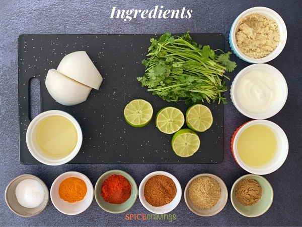 Ingredients for making Whole Tandoori Chicken spread out on a black cutting board